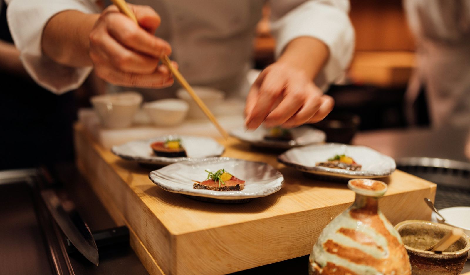 Handen van sushichefs serveren bordjes aan de counter